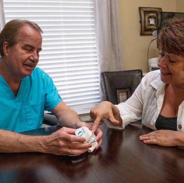 dentist with patient showing mouth model
